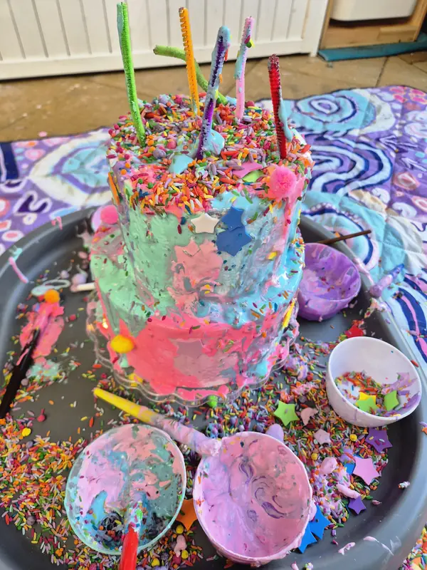 The finished play cake covered in swirls of coloured foam, sprinkles, stars and straw candles.